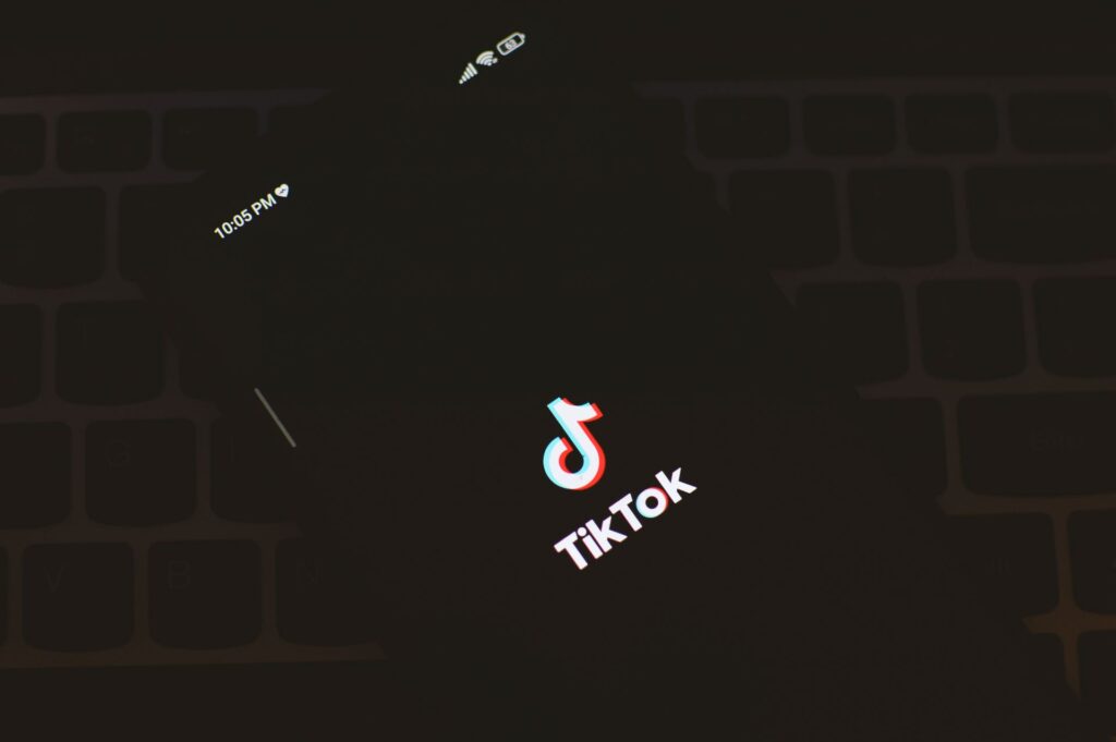 TikTok app logo glowing on a phone screen in a dark room.